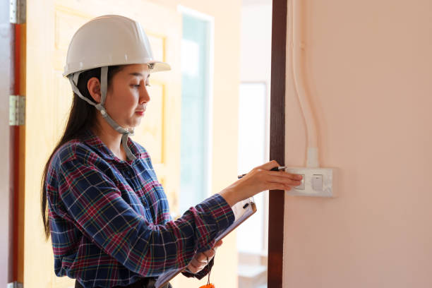Asian female in plaid shirt, white safety helmet, inspecting electric switch, with clipboard, indoors, meticulous assessment, professional home inspector. Inspectors inspect the completed house