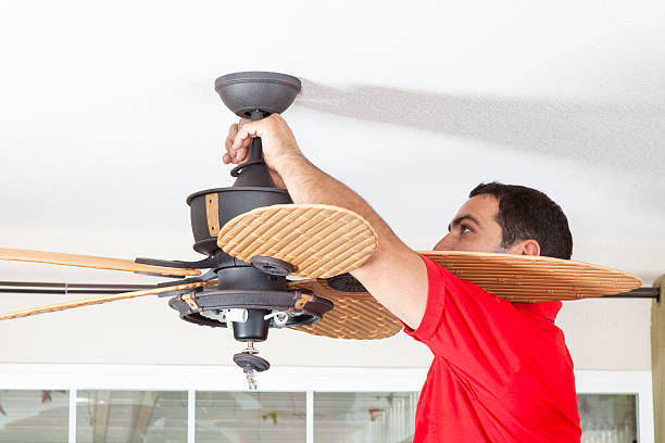 Men installing ceiling fan in a house.